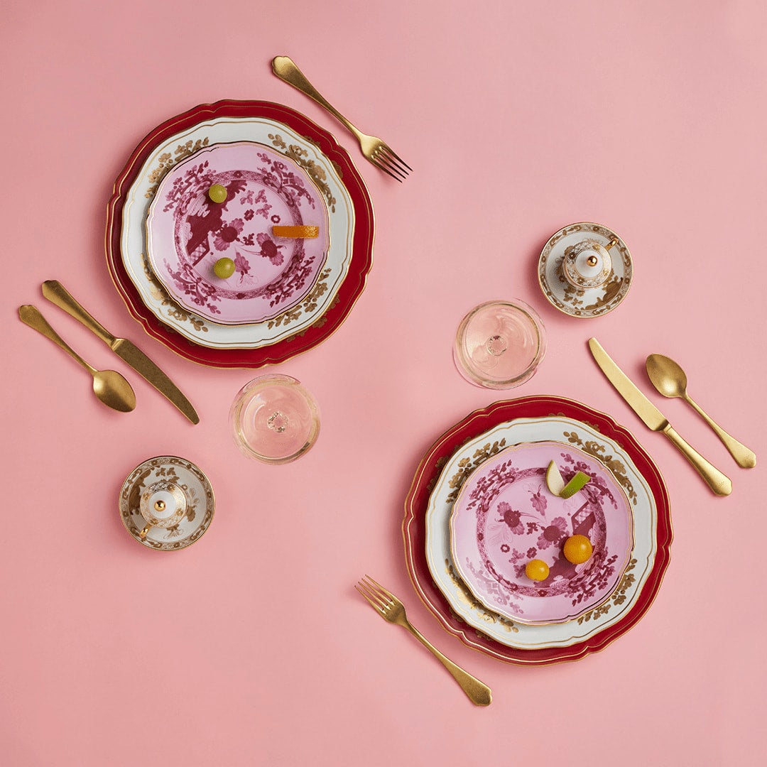 Pink and red Ginori 1735 place settings with gold cutlery on pink