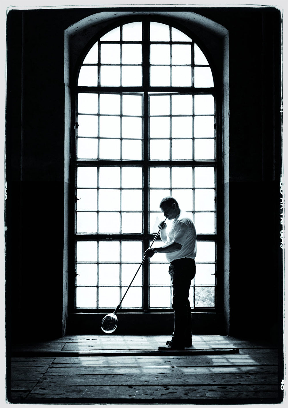 Baccarat glassblower at work before a tall arched workshop window