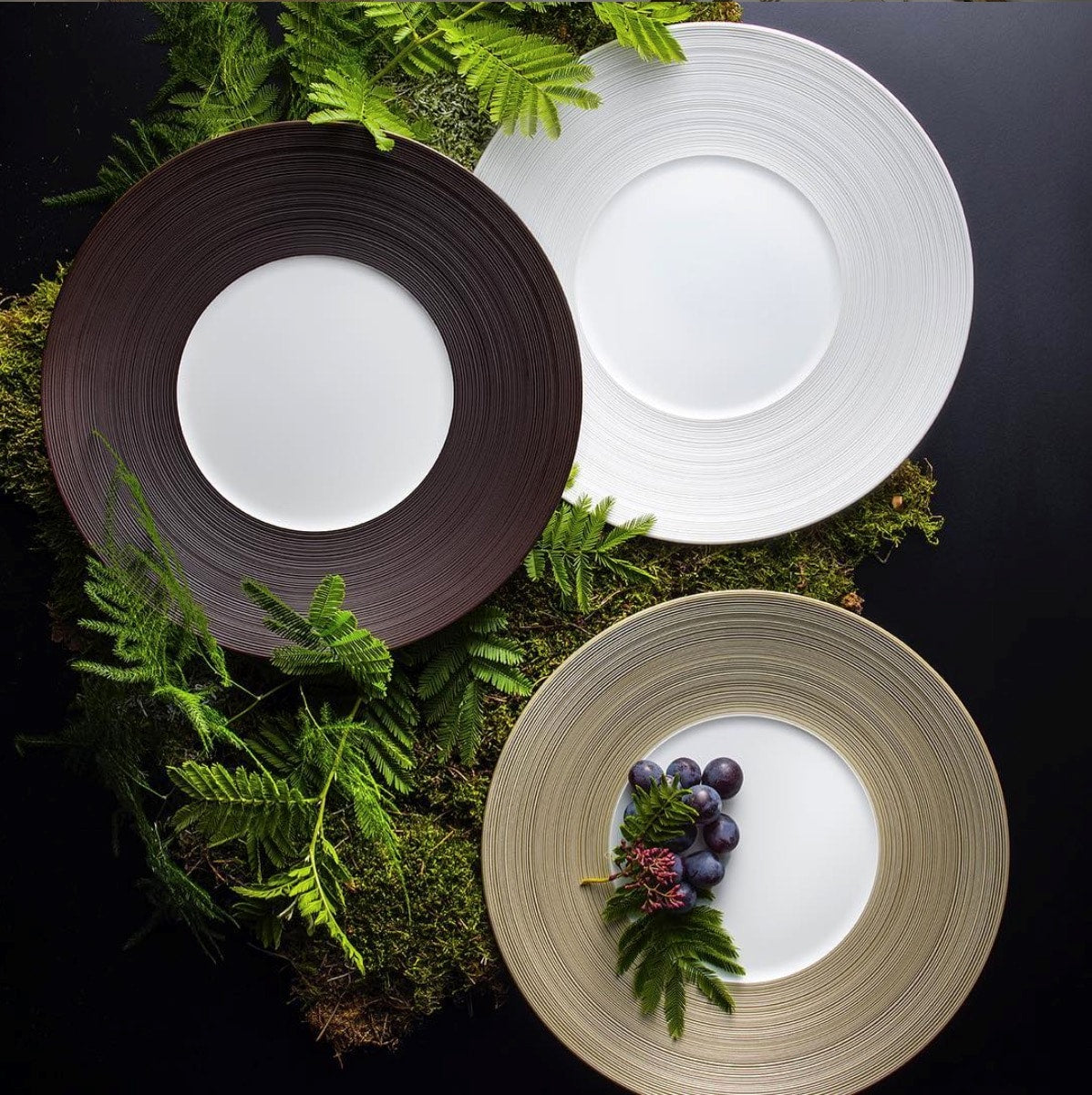 J.L. Coquet Hemisphere plates in brown, white and gold among ferns