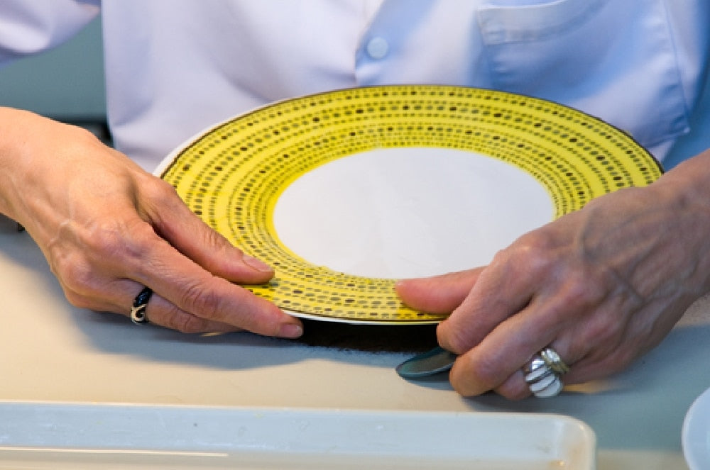 Hands holding a Seignolles plate with a yellow patterned rim