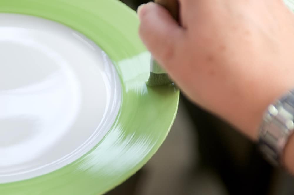A green band being applied to the rim of a Seignolles porcelain plate