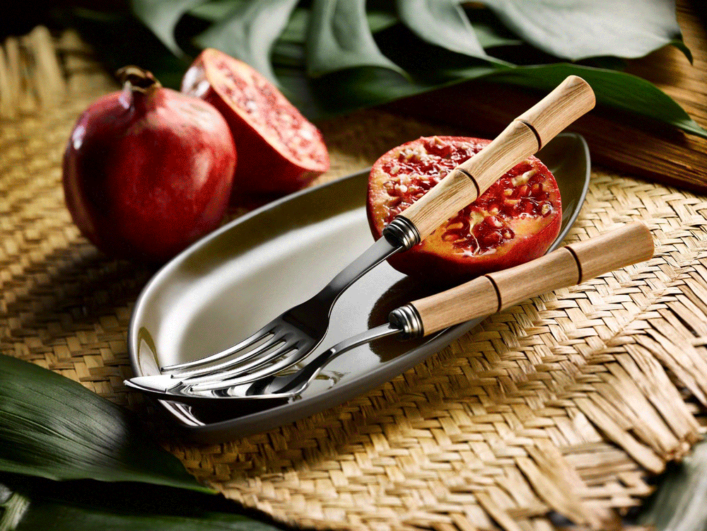 Sabre cutlery with bamboo-style handles beside pomegranates