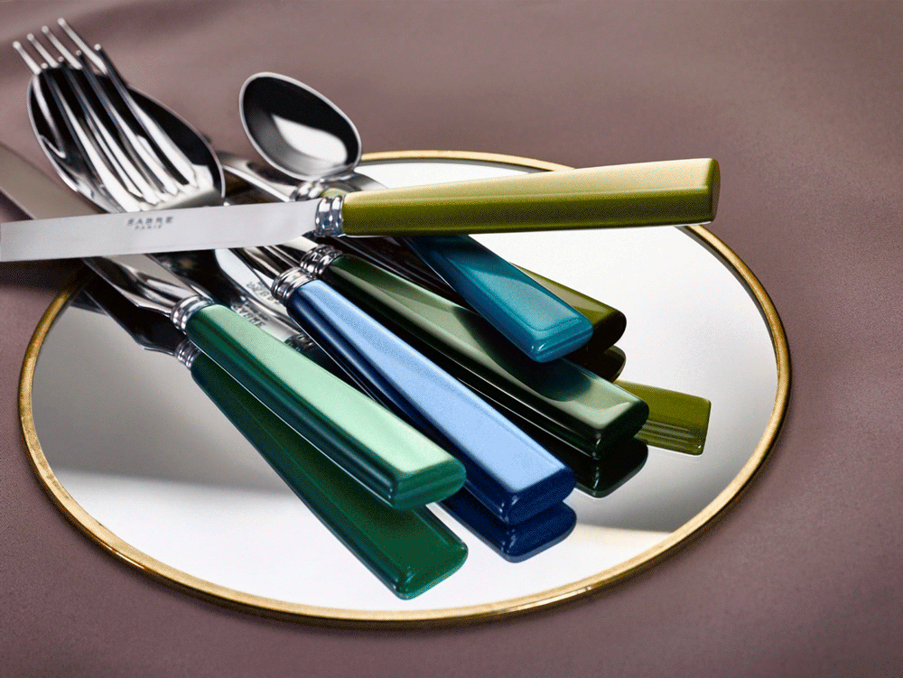 Sabre cutlery with green and blue handles on a gold-rimmed plate