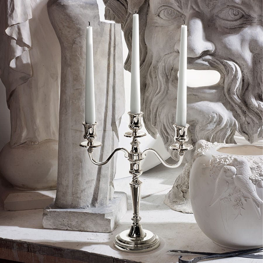 Ercuis silver three-branch candelabra with white candles beside classical plaster busts
