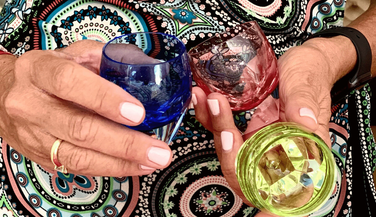 Coloured crystal glasses held in two hands