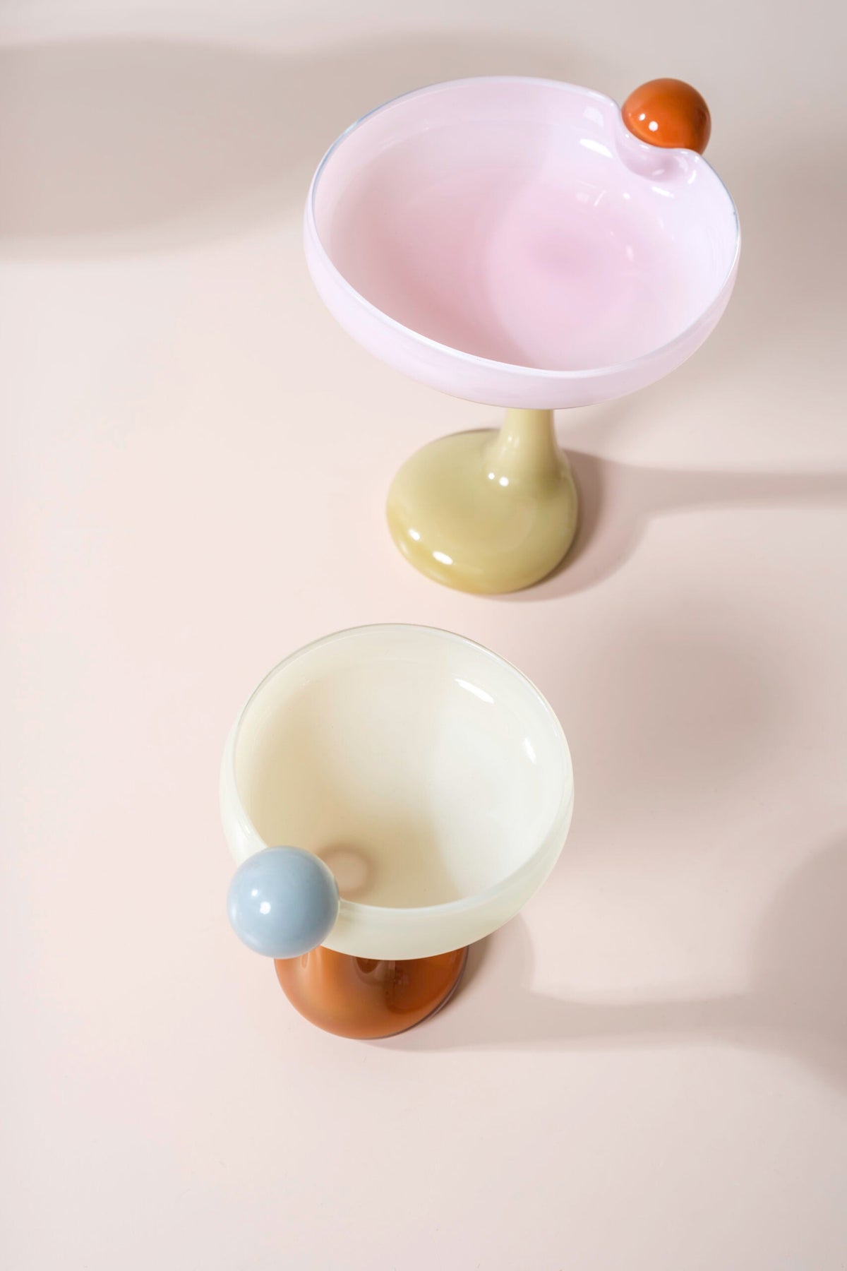 Two Helle Mardahl glass coupes in pink and cream, each with a coloured glass ball