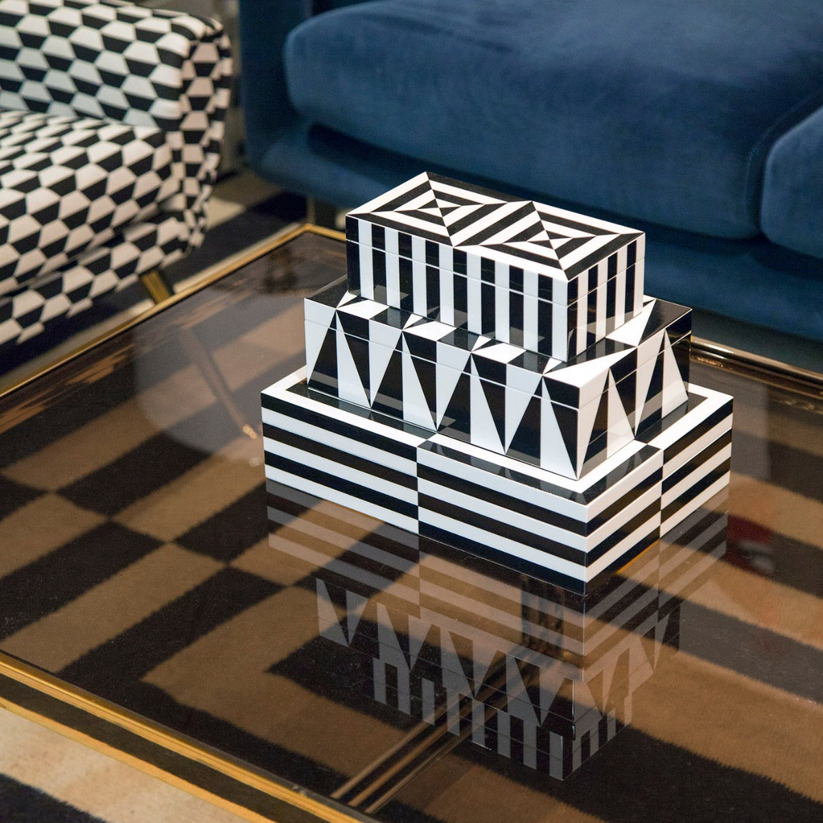 Black and white striped Jonathan Adler lacquer boxes on a glass table