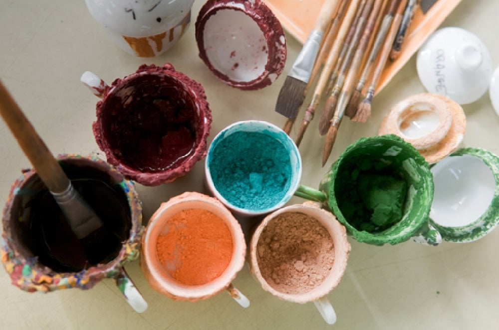 Pots of coloured pigment and brushes in the Seignolles workshop