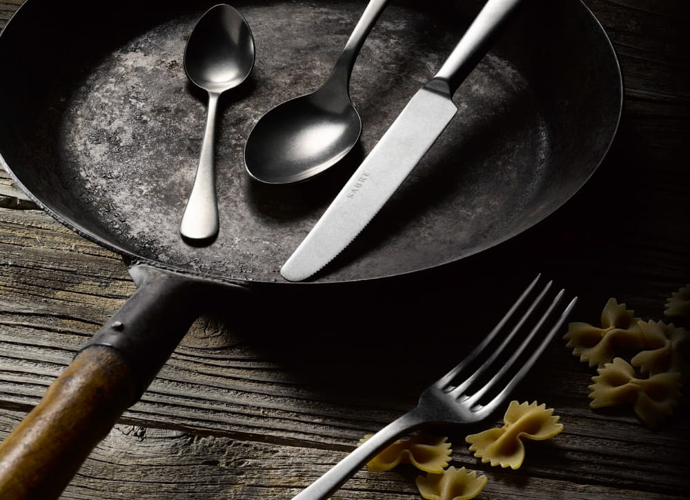 Brushed stainless steel Sabre cutlery in a cast-iron pan