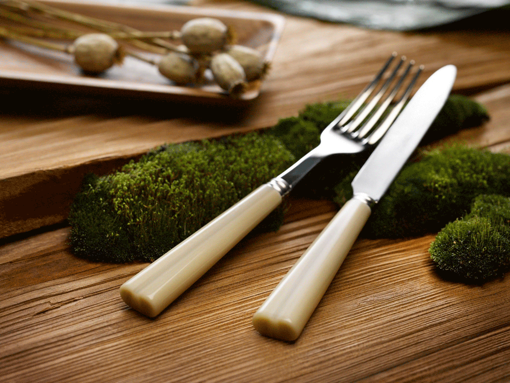 Sabre fork and knife with ivory-coloured handles on a wooden table