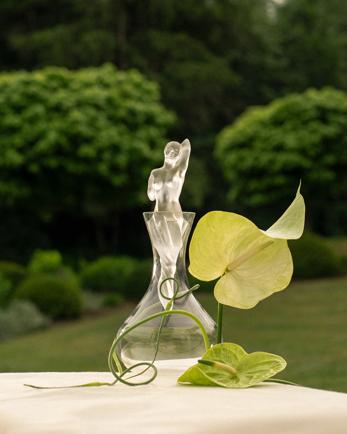 Lalique crystal carafe with a female figure stopper in a garden