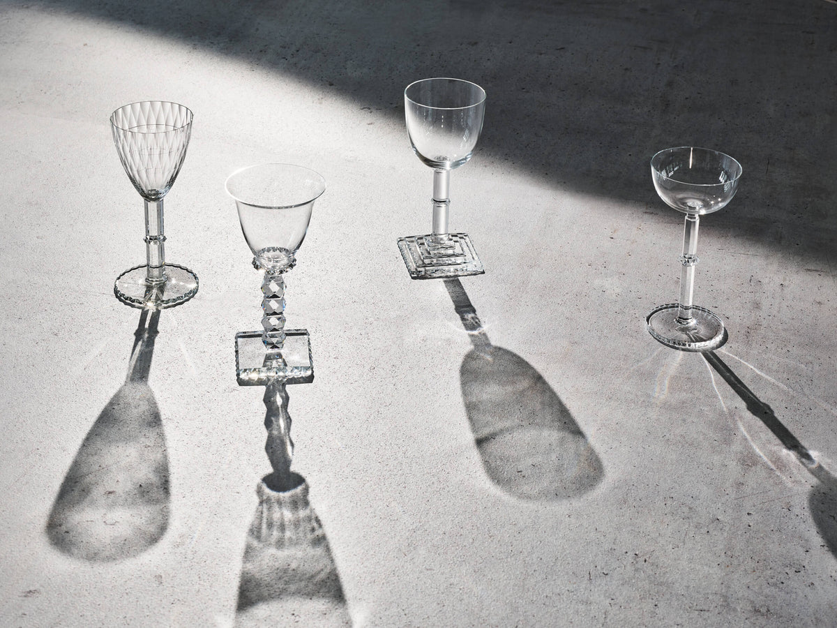 Four Lobmeyr stemmed glasses casting shadows in the sun